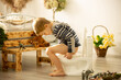 Cute toddler child, boy, using potty at home, while playing with toys