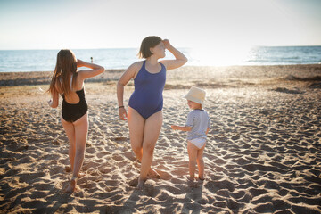 Wall Mural - Three children of girls in swimsuits run on the sand and play on the beach. Summer holidays and adventures of siblings. Active games on the sea coast. overweight child