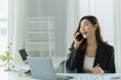 © PaeGAG - Asian business woman using smart phone and laptop in office.