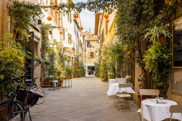  Beautifully landscaped narrow street with restaurant tables in the old town of Grosseto, in Maremma region of Italy. Cozy city view of the old Italian town