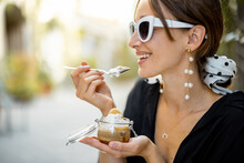 Woman eating tiramisu dessert at the restaurant outdoors. Concept of italian cuisine