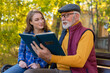 © Dexon Dee - Grandfather and granddaughter looking at photo album in park