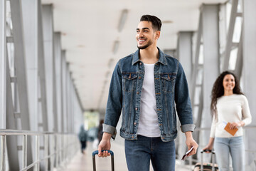 Wall Mural - Portrait Of Happy Arab Male Traveller Walking With Suitcase In Airport