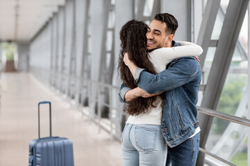 Wall Mural - Long Awaited Meet. Happy Arab Man Hugging Girlfriend At Airport After Arrival