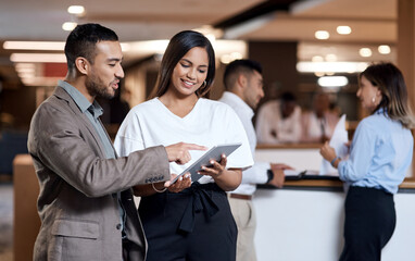 Every collaboration contributes to the bigger picture. Shot of a young businessman and businesswoman using a digital tablet at a conference.