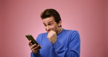 Man Amazed On Receiving Good News Using Mobile Phone Over Pink Background