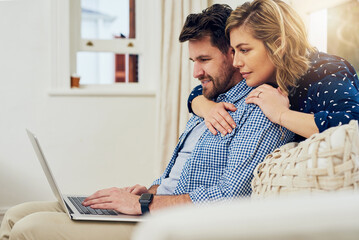 Poster - Browsing the internet together. Shot of an attractive couple using a laptop together at home.