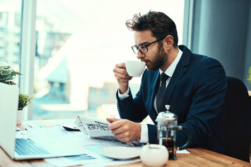 Sticker - Lets see how the markets are doing. Shot of a young businessman drinking a cup of tea while reading a newspaper in an office.