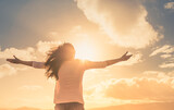 Fototapeta  - Young female with open arms feeling happy and free outdoors at sunset. 