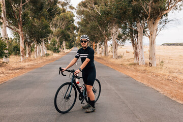 Wall Mural - Athlete taking a break from cycling on an empty country road