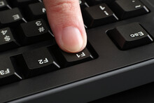 A Finger Pushing The F1 Key On A Black Computer Keyboard
