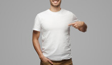 Young Man Pointing To His Blank White Tshirt With Index Finger, Showing Empty Space