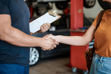 Wall Mural - We offer great service and advice. Shot of a woman shaking hands with a mechanic in an auto repair shop.