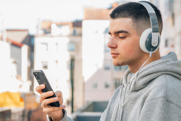 Wall Mural - young man with headphones and mobile phone listening to music on the street