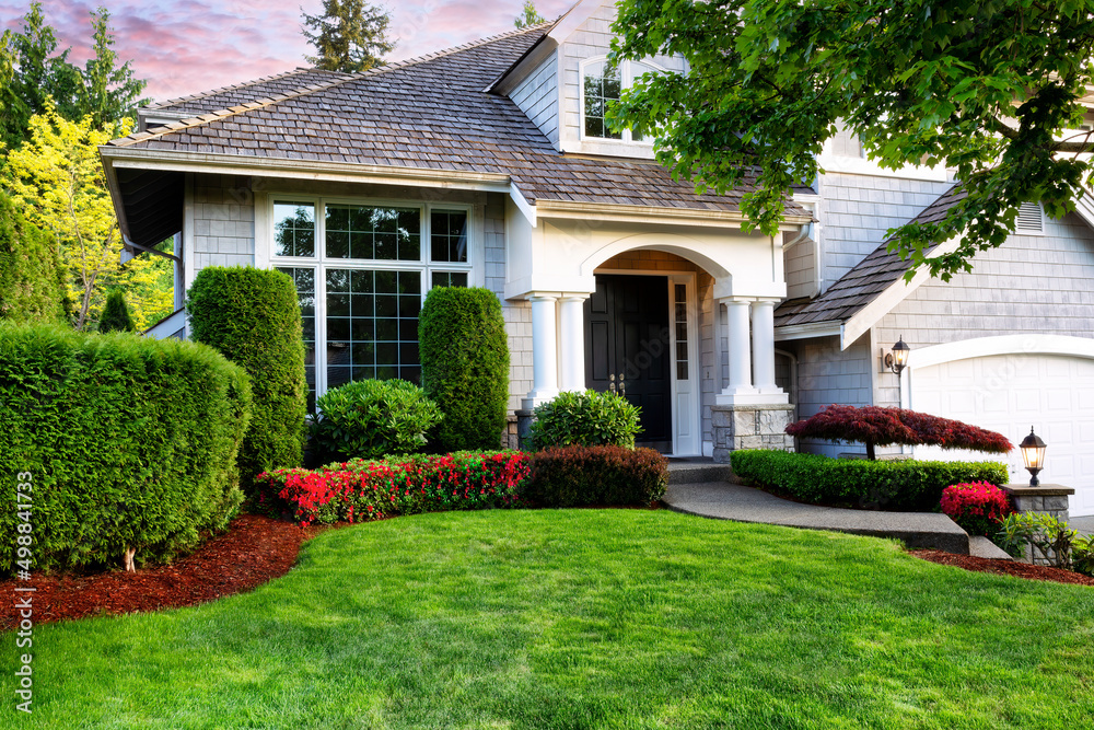 Beautiful home exterior in evening with healthy green lawn and ...