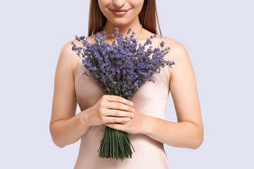 Wall Mural - Beautiful young woman with bouquet of lavender on light background