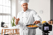 © Pixel-Shot - Male chef with fried vegetables recording video in kitchen