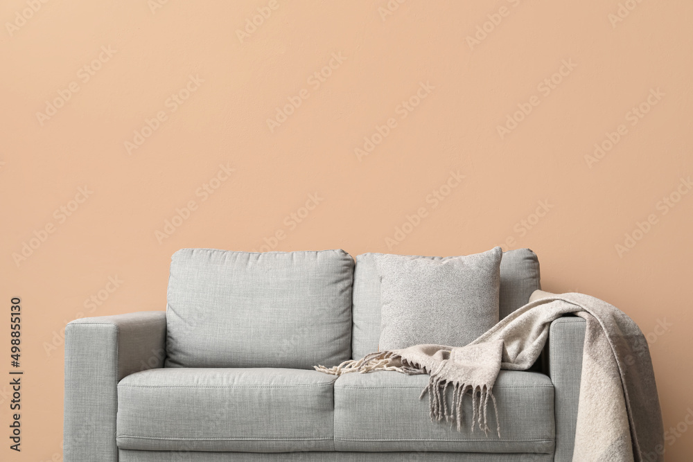 Comfortable sofa with plaid near beige wall