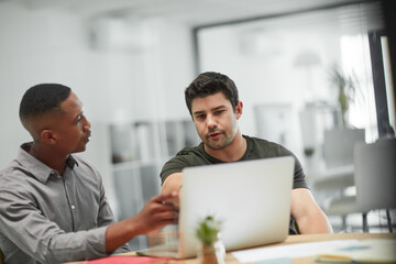 Canvas Print - Collaborations that produce results. Shot of two young businessmen using a laptop during a meeting in a modern office.