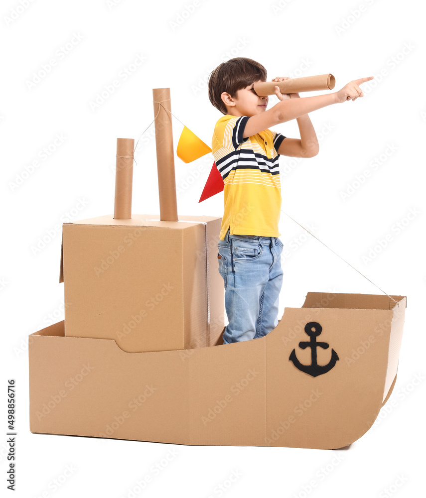 Cute little boy playing with cardboard ship on white background