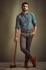 Poster - Dashing and daring. Studio shot of a young man posing with an axe against a green background.