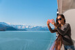 © Maridav - Alaska Glacier bay cruise ship travel tourist looking at icebergs taking pictures using phone in inside passage from balcony deck. Scenic cruising vacation destination panoramic banner