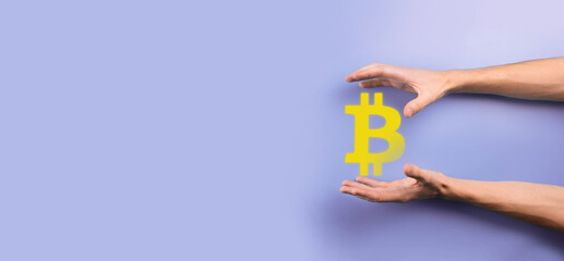 Male hand holding a bitcoin icon on blue background. Bitcoin Cryptocurrency Digital Bit Coin BTC Currency Technology Business Internet Concept.