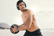 Music and exercise, now thats a good combination. Shot of a sporty young man wearing headphones while exercising outside with a medicine ball.