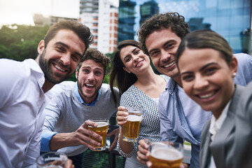 Wall Mural - Celebrating the end of year. Portrait of a cheerful group of young work colleagues getting close for a photo together while drinking beer outside during the day.