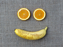 Flat Lay Two Round Orange Slices And Ripe Spotted Banana On Burlap Fabric