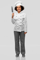 cooking, culinary and people concept - happy smiling female chef in white toque and jacket with kitchen knife over grey background