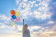 © Ryzhkov Oleksandr - Cheering young woman running on sunset grassland with balloons