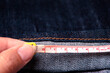 Hand of tailor measure the length of the jeans with a measuring tape
