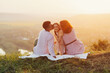 Young beautiful family with a little daughter on the hill at sunset. Parents hug and kiss their happy daughter. Family with a small child in nature.