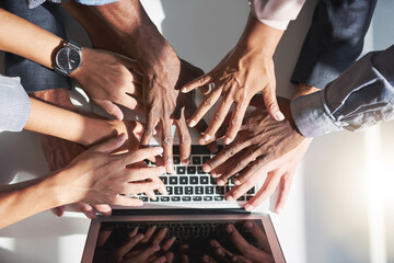 Canvas Print - Paying their dues to wireless technology. High angle shot of a group of colleagues posing with their hands over a laptop in the office.