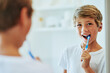 © K Seisa/peopleimages.com - Keeping my teeth strong. Shot of a cheerful young boy looking at his reflection in a mirror while brushing his teeth in the bathroom at home during the day.