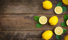 Composition Of Fresh Lemons And Slices With Leaves On A Wooden Background