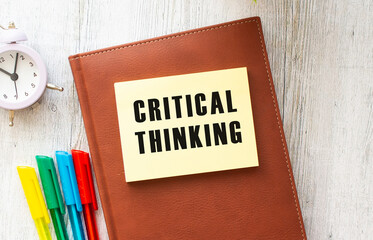 Notepad with text CRITICAL THINKING on a white background, near laptop, calculator.