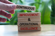 Hand holding wooden blocks with text - Continuous improvement and operational excellence.