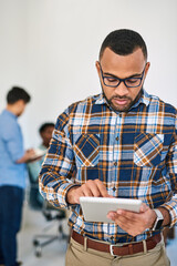 Poster - Meeting his managerial tasks with modern tech. Shot of a young entrepreneur using a digital tablet at work with his team in the background.