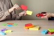 Women with toy car and color papers at wooden table indoors, closeup. ABA therapy concept