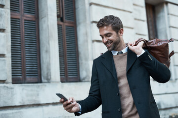 Poster - Staying in touch even when hes out and about. Cropped shot of a handsome businessman using his cellphone while about town.