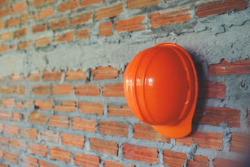 Wall Mural - Orange Safety helmet (hard hat) with brick background  in construction site.