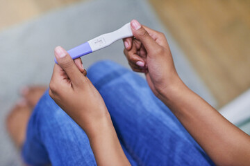 well, this is a surprise. shot of an unidentifiable woman holding a pregnancy test while sitting in 