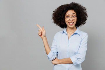 Wall Mural - Young employee business corporate lawyer woman of African American ethnicity in classic formal shirt work in office point index finger aside on workspace area isolated on grey color background studio.