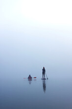 Vertical Image Of Two Women Paddling Kayak And Stand Up Paddle Board (SUP) At Autumn Misty River At Foggy Autumn Morning