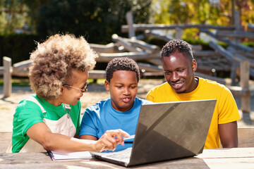 Portrait of happy afro parents and cute little boy using laptop together