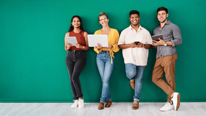Poster - Were always in the loop. Portrait of a group of young designers using digital devices while standing together against a green background.