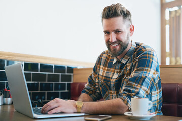 Poster - No coffee, no workee. Portrait of a young man using his laptop while sitting in a cafe.