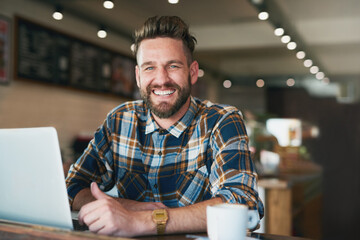 Poster - I like my internet connection as strong as my coffee. Portrait of a young man using his laptop while sitting by the window in a cafe.